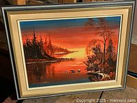 Framed oil on canvas landscape painting showing a sunset over a lake with trees and ducks, signed by Jean McCarthy