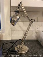 Full view of the vintage adjustable desk lamp showing the dome-shaped shade, articulated arm, and weighted base on a kitchen counter with white tiled backsplash.