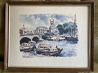 Full view of the framed mid century watercolour painting showing harbor scene with boats and church tower.