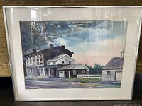 Framed watercolour painting showing a building landscape scene with road and sky, in silver frame