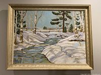 Full view of framed winter landscape painting showing snow, stream, trees and a barn in the distance.