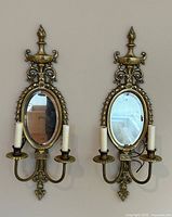 Pair of brass wall sconces mounted on neutral wall, showing full height and mirror reflectivity