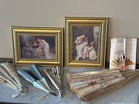 Two Victorian style framed prints in gold-tone frames with collection of antique and vintage handheld fans in varying designs and materials.