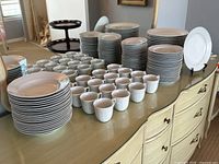 Overview of all stacked dinner plates, dessert plates, soup bowls, saucers and mugs on table