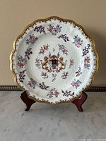 Full frontal view of white porcelain plate on wooden stand against beige wall