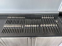 Overall layout of 59 pieces including forks, knives and spoons with black resin handles