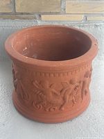 Front view of large terracotta planter featuring detailed cherub relief design.