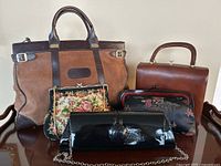 Lot of 5 vintage handbags: large brown suede and leather tote, floral needlepoint bag, brown leather boxy handbag, black satin embroidered clutch, and black patent leather chain clutch
