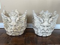 Front view of both planters side by side showing male face motifs