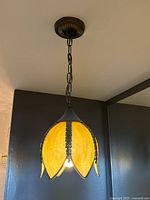 Photo of the slag glass pendant light hanging from the ceiling, showcasing the full pendant light including chain and mounting.