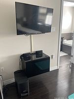 Full view of wall-mounted TV, speakers on cabinet and subwoofer on floor