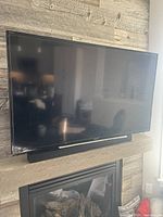 Sony Bravia 48in flat panel TV mounted above fireplace with soundbar below