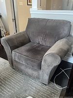 Gray upholstered chair and a half living room chair with visible texture on fabric, curved armrests, cushioned removable seat and cushioned backrest.