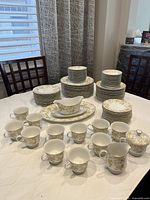 Wide view of complete dinnerware set including all plates, bowls, cups, and serving pieces arranged on table.