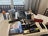 Desk and office items spread out on bed including desk lamp, trash can, letter trays, red pencil case, artist mannequin, tape dispenser, staplers, and various stationery items