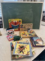 Photo showing chalkboard, Feed the Woozle game, books, wooden tangram puzzle, toy truck, and some flashcards.