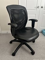Front view of the black office desk chair showing mesh backrest, padded armrests, and faux leather seat.