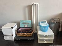 Wide view photo showing various organizational bins and baskets, laptop/tray, clear plastic drawers, blue basket, wicker basket, white storage boxes, trash can, and the painted IKEA spice shelf on the floor.