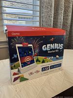 Front of Osmo Genius Starter Kit box showing the product and an iPad in the base stand.