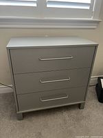 Front view of the small dresser showing three drawers with horizontal metal handles.