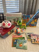Wide shot showing all major items in the lot including boxed toys, soccer ball, spaceship puller, books, and storage containers