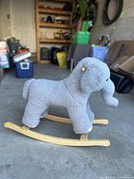 Full side view of the gray elephant rocking toy on wooden rockers on concrete floor in garage.