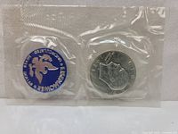 Front and back view of the 1974-S Eisenhower silver dollar sealed in original Blue Pack plastic packaging, showing the Blue Pack logo and the clear protective seal around the coin.
