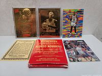 Front view of five items including three basketball trading cards, one holographic card, limited edition packaging, and information card.