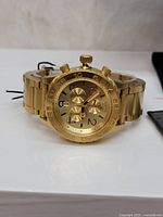 Front view of the Nixon gold-tone chronograph watch showing dial, chronograph subdials, and bracelet.