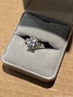 Front view of ring in box showing cluster setting and central stone