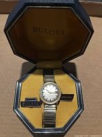 Top view of Bulova Aerojet watch in original octagonal box showing watch face, expansion band and branded plaques inside box.