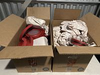 Two cardboard boxes filled with glass bowls and red lids, surrounded by crumpled packing paper.