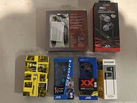 Photo showing six headphones/earbuds in their retail packaging from Skullcandy, JVC, PRO by Monster, and Koss brands