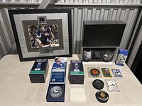 Overview of hockey memorabilia items on table including framed signed photo, bobbleheads, collectible pucks, glasses, and cards