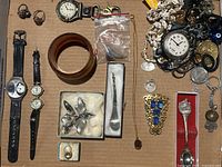 Full overview of jewelry contents including watches, brooches, rings, necklaces, bangle bracelet, and collectible spoons
