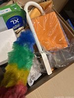 Snow globe, feather dusters, microfiber cloths, and cleaning supplies visible in box