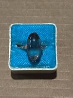 Top view of the silver ring with large elongated oval blue stone mounted horizontally.