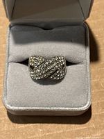Front view of vintage 925 silver ring with clear rhinestones in a twisted, overlapping design inside a gray velvet ring box.