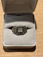 Ring in gray velvet display box showing front view