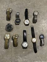 Full view of all 10 watches posed on concrete floor displaying varied styles and bands