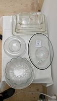 Top view of the Pyrex lot showing various glass baking dishes, round bowls including a bundt pan, and two measuring cups.
