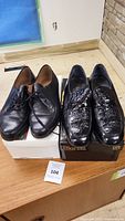 Two pairs of men's black leather dress shoes side by side, one smooth leather Bally pair and one crocodile-patterned Marant pair, both size 8.5.