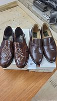 Photo of two pairs of men's brown leather Italian shoes displayed on boxes, showing overall condition and style.