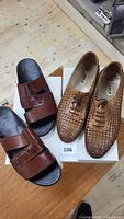 Two pairs of men's summer shoes, one brown woven leather lace-up shoes and one brown leather slide sandal, placed on white shoe boxes labeled Palvico.