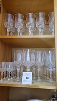 Shelves with multiple rows of clear vintage crystal stemware glasses arranged by size, showing ornate cut crystal pattern on bowls.