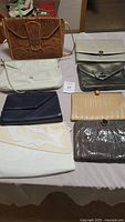 Lot of 8 vintage handbags in various colors and materials arranged on a table showing different styles and closures.