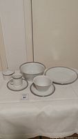 Overview of multiple porcelain pieces from the Rosenthal Studio-Linie set arranged on a table showing plates, bowls, cups, saucers, and sugar bowl.