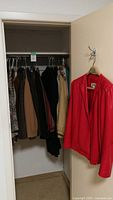 View of the clothing lot hung inside a closet showing multiple vintage women's garments size 10 including blazers and shirts in neutral and patterned colors.