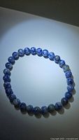 Blue sodalite stretchy bracelet laid flat in circular form, showing blue and white marbled beads.
