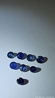 Photo of nine round cut natural blue sapphires in various shades of cornflower and royal blue. Stones appear faceted and approximately 2.8mm each.